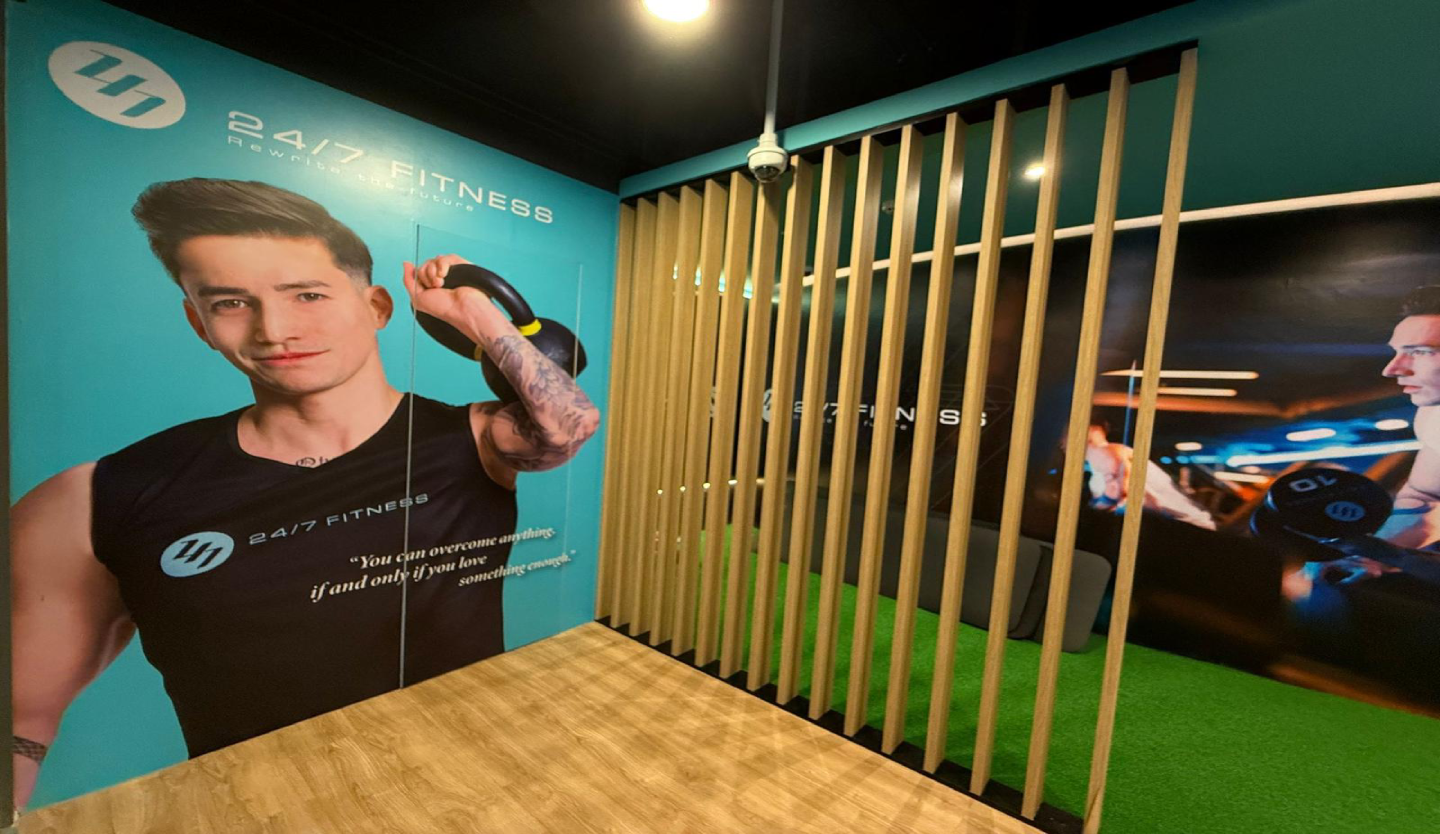 247 Fitness gym feature wall fit-out by Trident Fitout, brand poster beside a timber slat partition