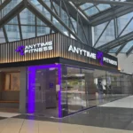 Anytime Fitness gym storefront fit-out by Trident Fitout, corner unit beneath a steel-framed glass atrium next to Sky Garden Restaurants and Bars
