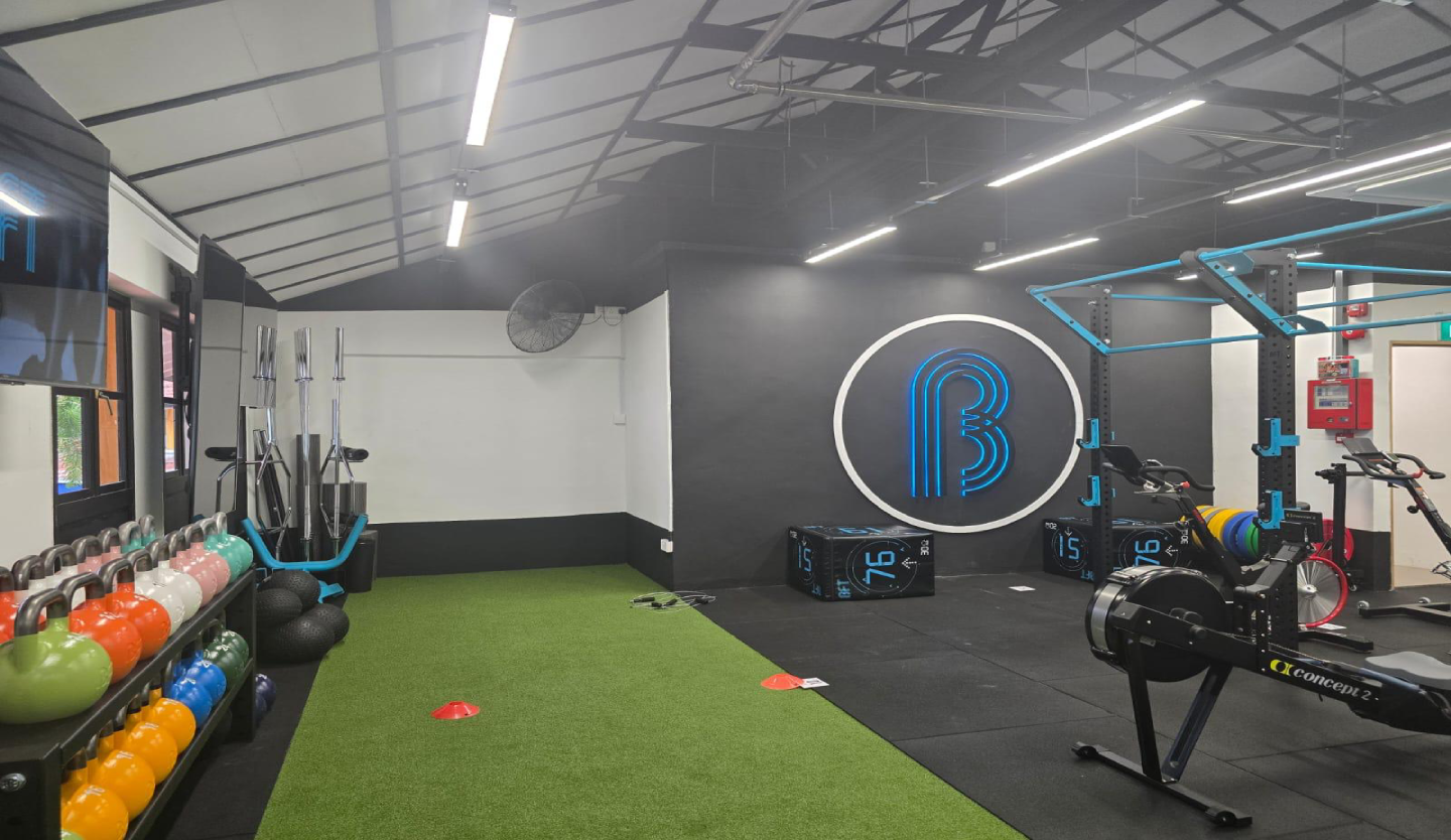Body Fit Training gym fit-out by Trident Fitout, kettlebell rack and rowing machines beneath a backlit B logo