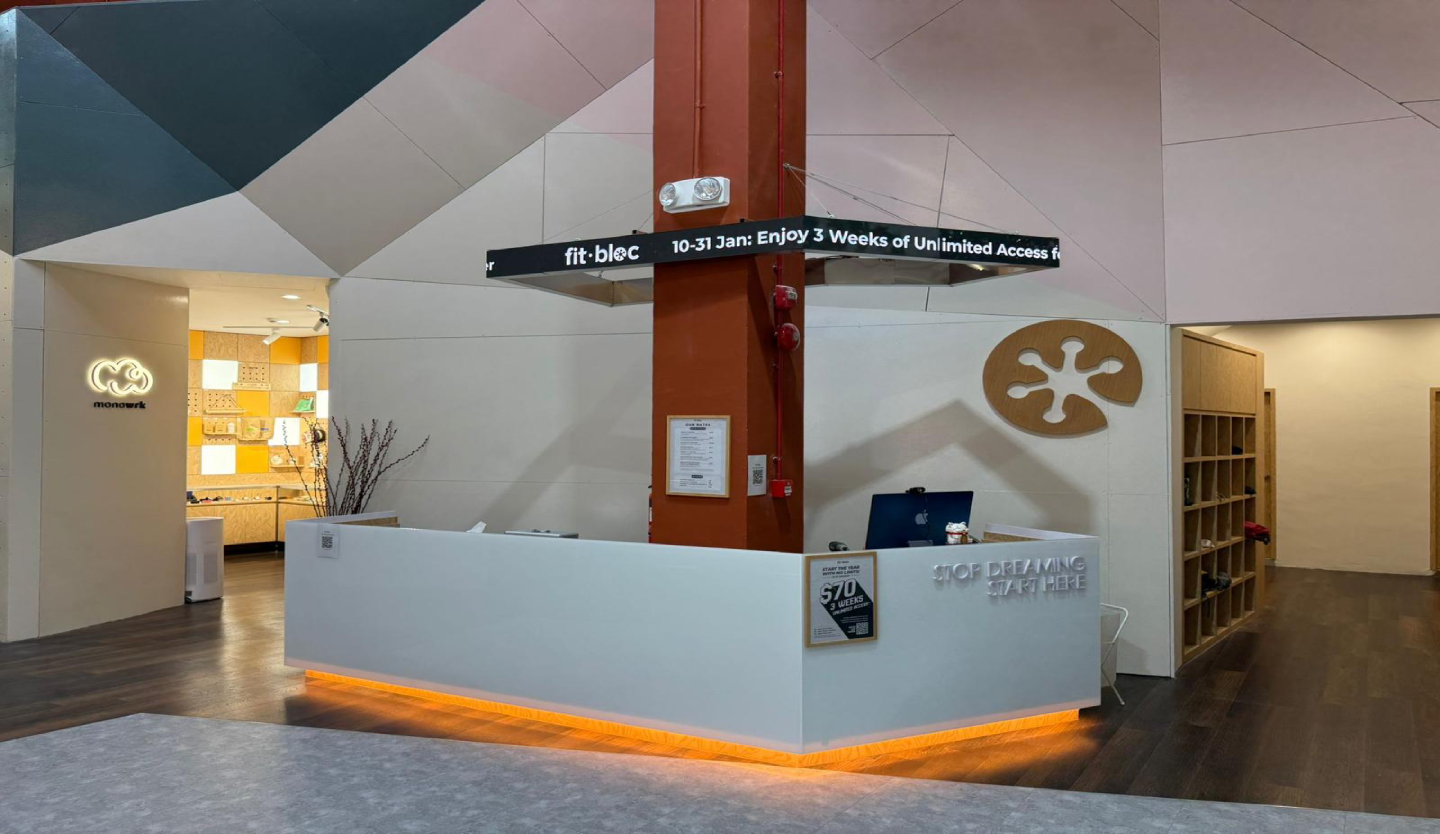Fitbloc reception counter fit-out by Trident Fitout, backlit logo and orange under-lighting beside the shoe cubby wall