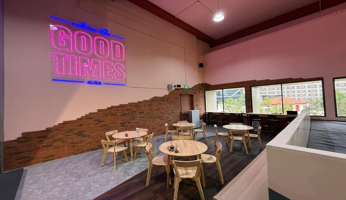 Fitbloc cafe and lounge fit-out by Trident Fitout, seating beneath a neon sign and part-exposed brick feature wall