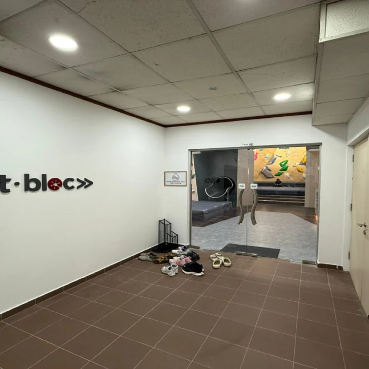 Fitbloc entrance fit-out by Trident Fitout, corridor with a shoe rack leading through glass doors to the climbing wall