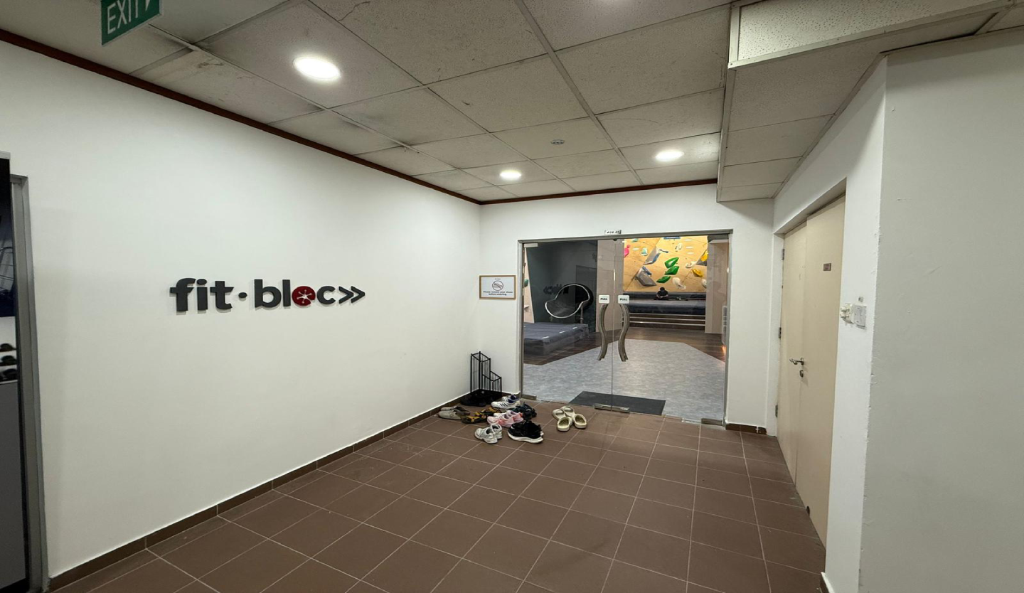 Fitbloc entrance fit-out by Trident Fitout, corridor with a shoe rack leading through glass doors to the climbing wall