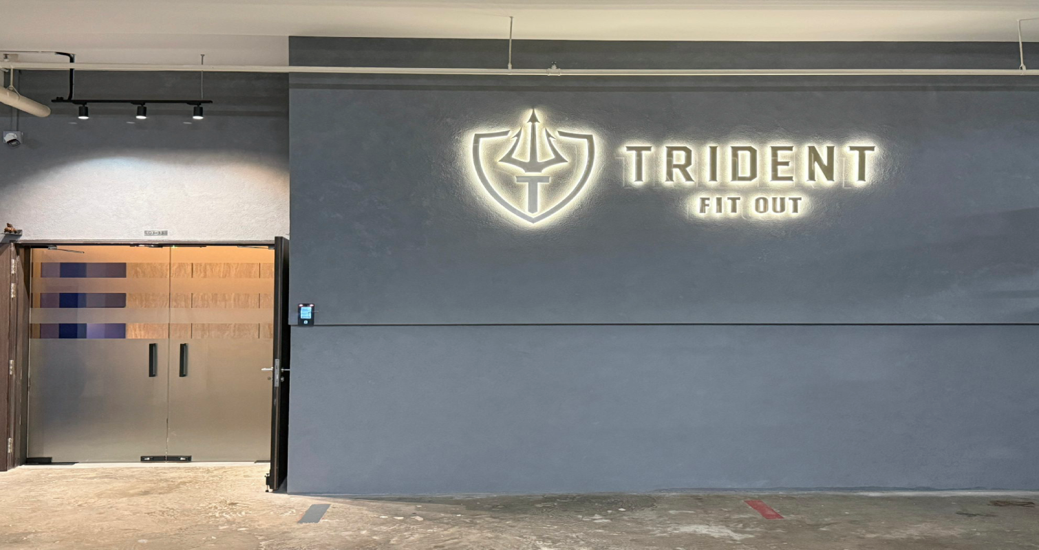 Trident Fitout site signage, backlit gold shield and trident logo on a feature wall inside the office under fit-out