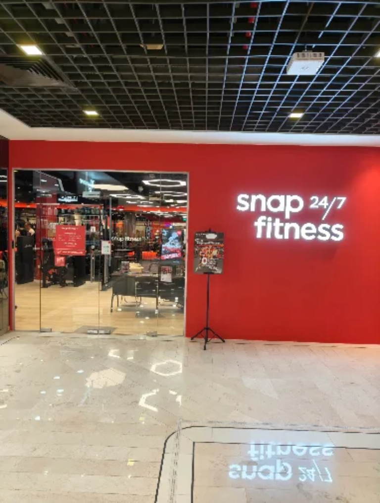 Snap Fitness gym storefront fit-out by Trident Fitout, red feature wall beneath an exposed grid ceiling