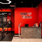 Snap Fitness gym reception fit-out by Trident Fitout, red feature wall with the training floor reflected in the mirror behind