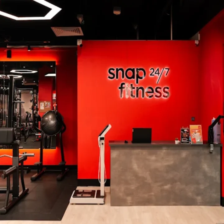 Snap Fitness gym reception fit-out by Trident Fitout, red feature wall with the training floor reflected in the mirror behind