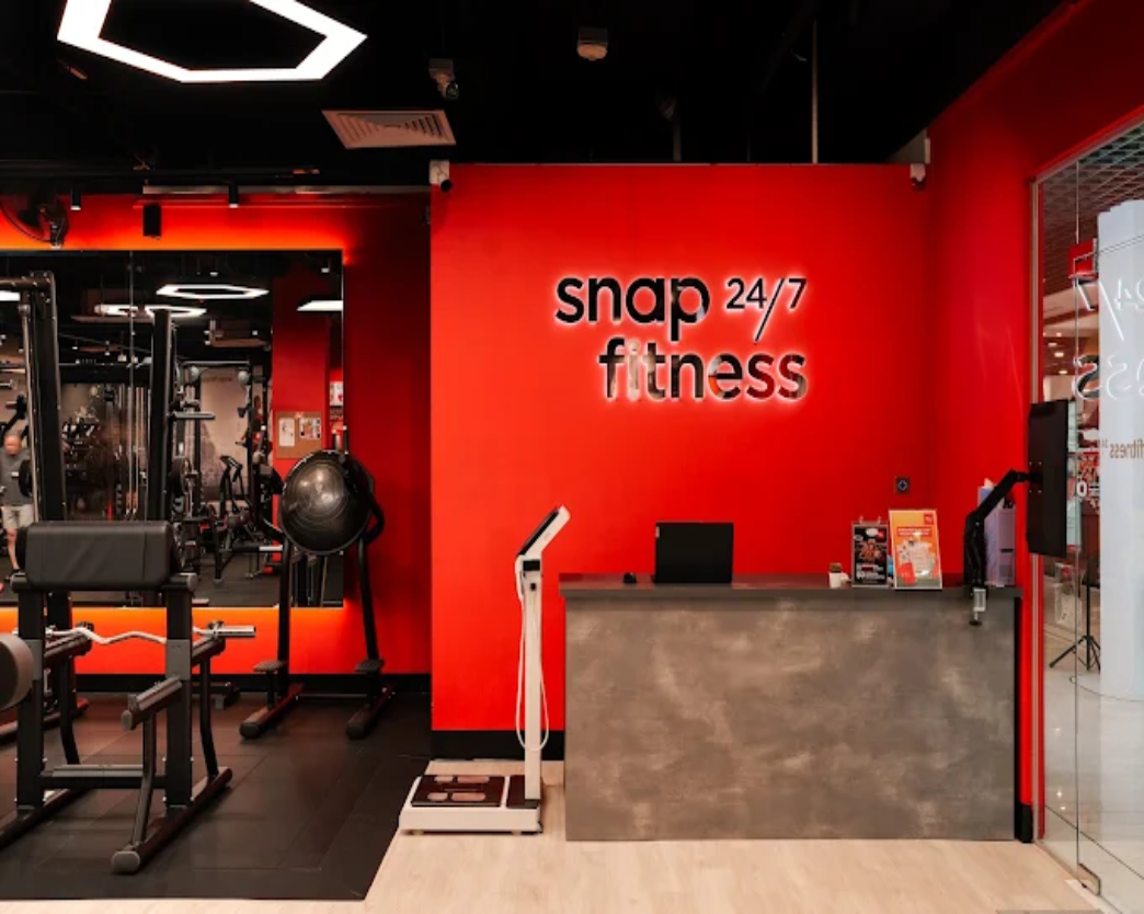 Snap Fitness gym reception fit-out by Trident Fitout, red feature wall with the training floor reflected in the mirror behind