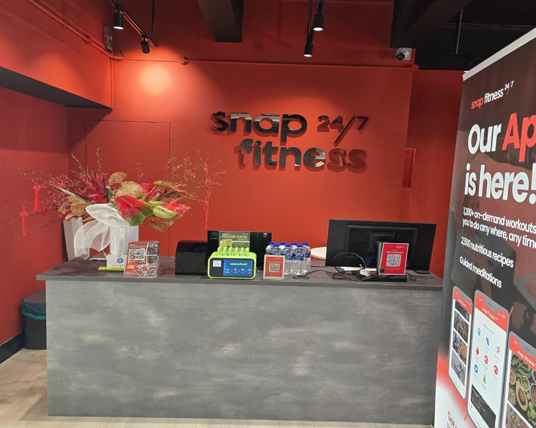 Snap Fitness gym reception counter fit-out by Trident Fitout, red feature wall with a festive flower arrangement on the counter