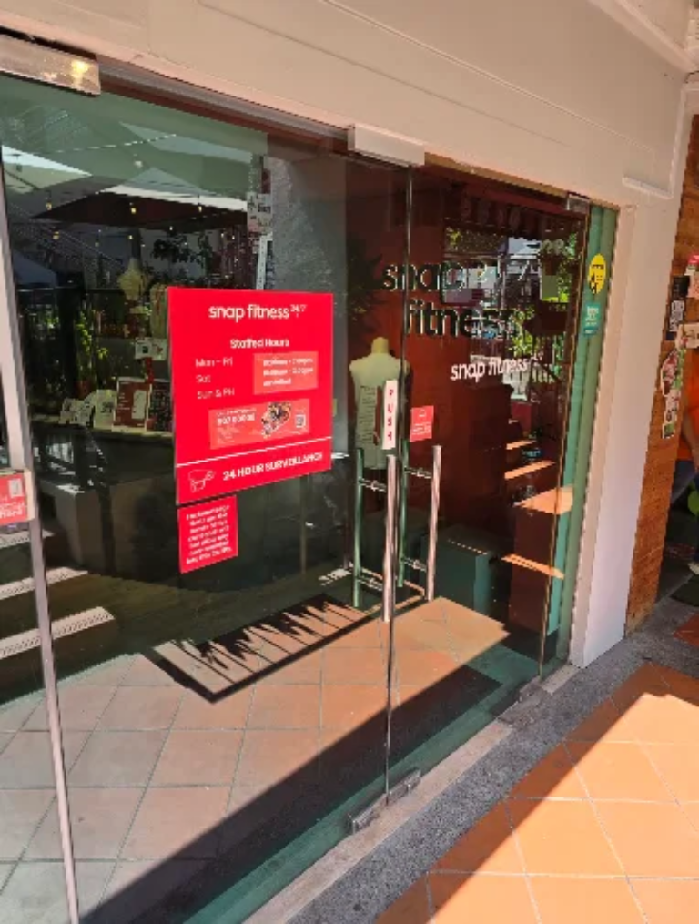 Snap Fitness gym entrance fit-out by Trident Fitout, glass doors with cursive-style signage and a floral stand at the entrance